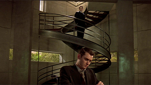 Vincent, en haut d'un escalier regarde Jerome en bas, sur son fauteuil roulant qui lui tourne le dos